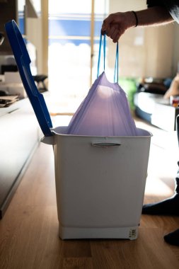 Adamın biri çöp torbasını çöpten çıkarıyor. Temizliği ve ev temizliğini sürdürmek.