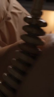 Kadın, midesinde dero terapisiyle anti-selülit masaj seansı yapıyor. Profesyonel terapist stüdyoda tahta silindir tutuyor..