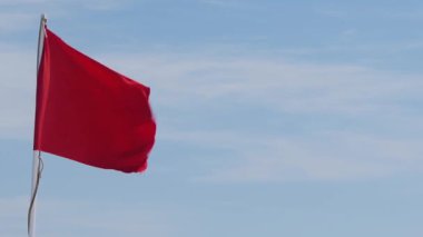Cesur Amblem: Açık Mavi Gökyüzüne Karşı Çarpıcı Kırmızı Bayrak