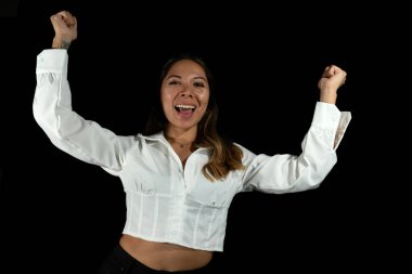 celebrate beautiful latina woman, with brown and golden hair and brown skin posing and looking at the camera with black background white shirt melted black background. clipart