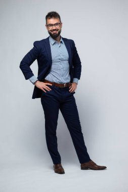 Kendine güveni tam bir İspanyol portresi, şık mavi bir takım elbise giymiş, elleri kalçasında ve yumuşak bir gülüşü olan. Onun rahat duruşu ve açık duruşu rahatlık, güven ve modern profesyonelliği iletir..