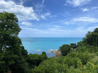 Okyanus manzaralı bir tepeden su taşları, uçsuz bucaksız mavi gökyüzü bulutlu