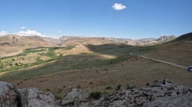 Büyük Kazak bozkırının 4K panoraması. Tepeler, kayalar, çalılar ve mavi gökyüzü. Yumuşak kamera hareketi