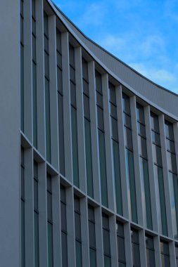 Arka planda mavi gökyüzü olan bir iş binasının modern cephesi Cheltenham, İngiltere