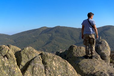 Dağın tepesindeki adam uzaklara bakıyor.