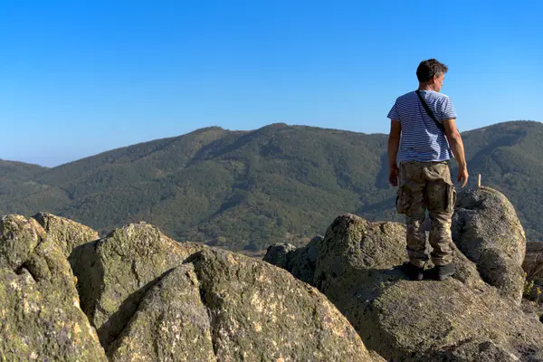 Dağın tepesindeki adam uzaklara bakıyor.