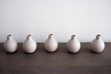 Tahta bir masada bej vazolar. Bir grup küçük kahverengi sürahi. Ahşap bir yüzeyde kil çömlekler. Atıcılar yakın çekim.