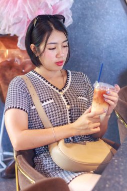 Elimde tuttuğum Tayland çayına bakan Asyalı kadın portresi.