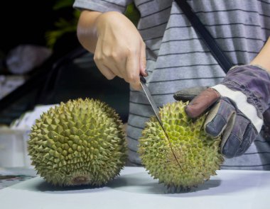 Bıçak tutan, deri eldiven giyen Taylandlı bir kadının eli. Durian 'ın kabuğunu soyup, Tayland meyvesi hamuru isteyecekler..