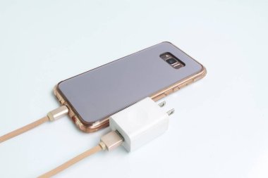Beyaz arkaplandaki USB kablosu üzerinden Smartphone 'un şarja bağlanmasını geri görüntüle