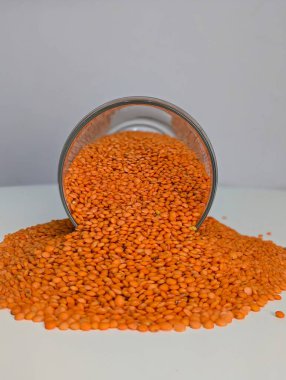 Parlak turuncu mercimeklerin yakın plan çekimi temiz beyaz bir yüzeye yayılarak zengin, topraksı tonlarını ve pürüzsüz dokularını gözler önüne seriyor. Bu resim mercimekleri protein, lif ve temel minerallerle dolu besleyici bir zımba olarak vurgular.. 