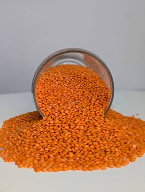 Parlak turuncu mercimeklerin yakın plan çekimi temiz beyaz bir yüzeye yayılarak zengin, topraksı tonlarını ve pürüzsüz dokularını gözler önüne seriyor. Bu resim mercimekleri protein, lif ve temel minerallerle dolu besleyici bir zımba olarak vurgular.. 