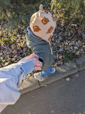 İki yaşındaki bir çocuğun, annesinin elini tutarken, vücudunu kasıtlı olarak çerçevenin dışında tuttuğu hassas bir an. Çocuğunuzun küçük eli annelerini kucaklıyor. Yürek ısıtan bir bağ, sevgi ve güven hissi veriyor.. 