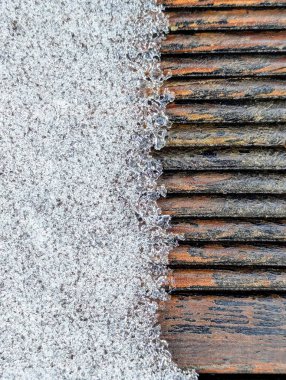 Yakın plan bir fotoğraf, yeni yağan karı, ahşap bir yüzeyi nazikçe örterek, soğuk, beyaz kar ve sıcak, desenli ahşap arasındaki karmaşık etkileşimi vurgular.. 