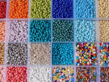 Plastik bölme kutusunda düzenlenmiş renkli parlak kristal boncuklar.