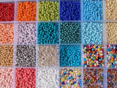 Plastik bölme kutusunda düzenlenmiş renkli parlak kristal boncuklar.