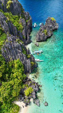 A breathtaking tropical lagoon surrounded by dramatic limestone cliffs and lush greenery, with crystal-clear turquoise waters and traditional boats docked along the shoreline. This stunning scene clipart