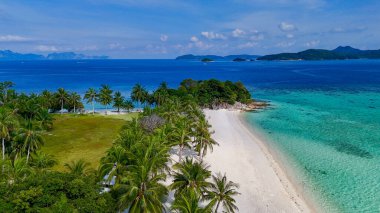 Beyaz kumlar, turkuaz sular ve sıra sıra yemyeşil palmiye ağaçlarının bulunduğu el değmemiş tropikal bir plajın çarpıcı hava manzarası. Cennet gibi ada manzarası, rahatlık ve doğanın mükemmel bir karışımını sunuyor.