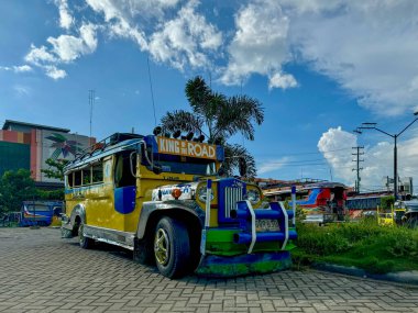 A brightly colored traditional jeepney parked under a sunny blue sky in the Philippines. Known as the King of the Road, this iconic mode of transportation showcases the vibrant culture and heritage of clipart