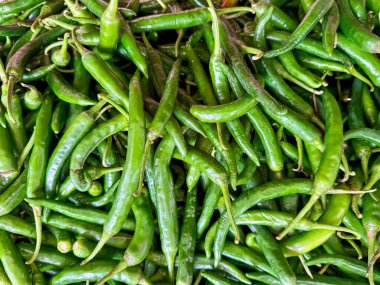 A vibrant close-up of fresh green chili peppers, showcasing their shiny texture and vivid color. The perfect representation of spicy produce in a bustling market setting. High quality photo clipart