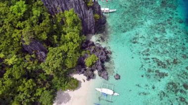 Filipinler 'in kristal berrak sularına demirlenmiş kireçtaşı kayalıklarının ve geleneksel teknelerin büyüleyici güzelliğini keşfedin. Bu hava görüntüleri canlı deniz yaşamını, dramatik kayayı vurguluyor.