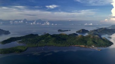 Sakin mavi sularla çevrili yemyeşil adaların ve sakin gökyüzünün altındaki uzak adaların çarpıcı hava manzarası. Tropikal güzellik ve sükunetin mükemmel bir temsili, seyahat için ideal ve...