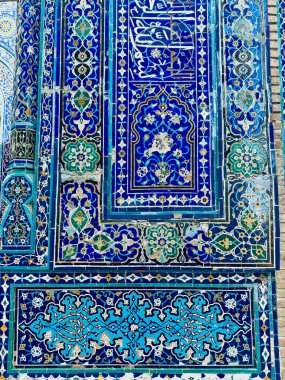 Geleneksel İslami kalıplar ve kaligrafi ile süslenmiş, çarpıcı bir işçilik ve kültürel miras sergilenen karmaşık detaylı mavi mozaik duvarın canlı bir yakın çekimi..