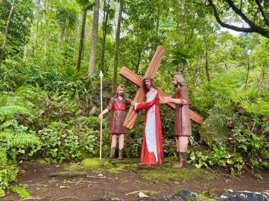 Hz. İsa 'nın haçı taşıyan gerçek büyüklükteki heykelleri ve yemyeşil bir tropikal ormanda geçen diğer iki figürün yer aldığı dini bir sahne. Heykeller canlı yeşil yapraklarla çevrili.