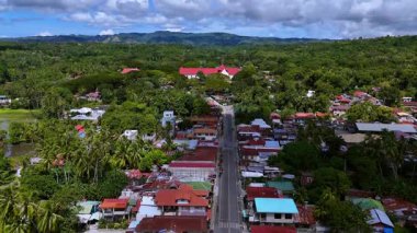 Yeşillik ve dağlarla çevrili tropikal bir kasabanın çarpıcı hava görüntüleri. Videoda kırmızı çatılı tarihi bir kilise, geleneksel ve modern evlerin bir karışımı ve bir ana cadde yer alıyor.