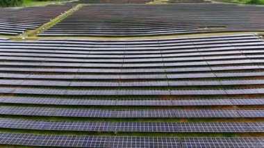 Geniş bir güneş enerjisi çiftliği, binlerce fotovoltaik panelin mükemmel simetride hizalandığı ufka doğru uzanıyor. Bu büyük ölçekli yenilenebilir enerji projesi güneş ışığını yakalıyor.