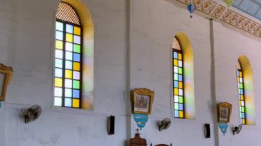 Pastel mavi tavanı, karmaşık altın detayları ve renkli sıcak hava balonu süslemeleri olan güzel dekore edilmiş bir Katolik kilisesi. Güneş ışığı vitray pencerelerden süzülür
