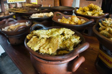 Endonezya 'nın çeşitli geleneksel kızartılmış atıştırmalıkları kil kaplar, canlı dokular ve zengin tatlar ile sunulmaktadır. Toprak sunumu mutfağın özgün ve zanaatkar doğasını vurgular..