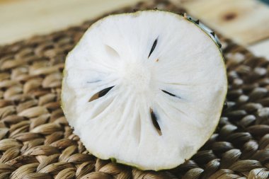 Beyaz bir plaka üzerine yerleştirilmiş yarım yamalak bir meyvenin yakın plan görüntüsü doğal, dokunmuş bir arka plana karşı, dokusu, rengi ve egzotik çekiciliği vurguluyor.