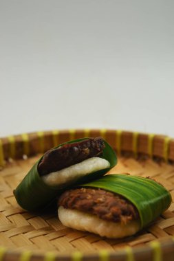 Indonesian traditional snacks of tempe paired with white Jadah rice, uniquely wrapped in fresh banana leaves offering a cultural culinary experience clipart