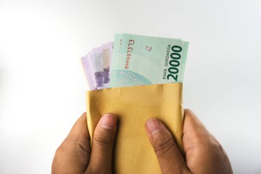 A pair of hands holds an envelope filled with Indonesian rupiah banknotes. The presentation emphasizes finance, savings, and monetary concepts, ideal for illustrating economic or personal financial themes clipart