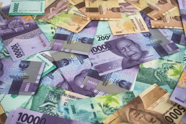 Endonezya para birimi notları, renkli bir dizi ve bankacılık, finans ve yatırım kavramlarını canlı ve göz alıcı bir kompozisyonda temsil eden rastgele yayılmış banknotlar sergiliyor..