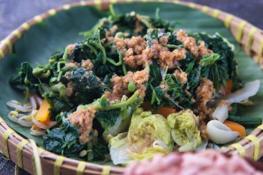 Pecel Geleneksel Endonezya Sebze Salatası. Muz yaprakları üzerinde sunulan fıstık sosuyla servis edilen renkli buharlı sebzeler geleneksel Endonezya stili ve sağlıklı bir akşam yemeği.