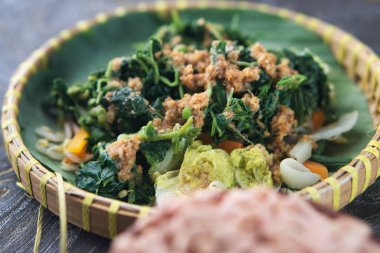 Pecel Geleneksel Endonezya Sebze Salatası. Muz yaprakları üzerinde sunulan fıstık sosuyla servis edilen renkli buharlı sebzeler geleneksel Endonezya stili ve sağlıklı bir akşam yemeği.