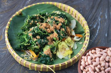 Pecel Geleneksel Endonezya Sebze Salatası. Muz yaprakları üzerinde sunulan fıstık sosuyla servis edilen renkli buharlı sebzeler geleneksel Endonezya stili ve sağlıklı bir akşam yemeği.