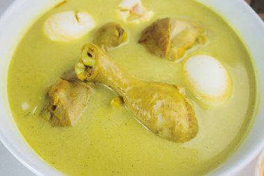 Sarı köri (opor ayam) ve ketupat pirinç keklerinin yer aldığı geleneksel Endonezya yemeği, bir kutlama veya şenlikli yemek deneyimi sunar.