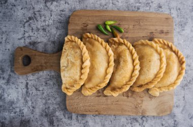 Kue Pastel or Jalangkote, Indonesian traditional snack filled with carrot and potatoes served On Wooden Cutting Board With Fresh Green Chilis clipart