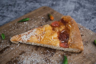 Tahta kesme tahtasının üzerinde kalan son dilim pizza.