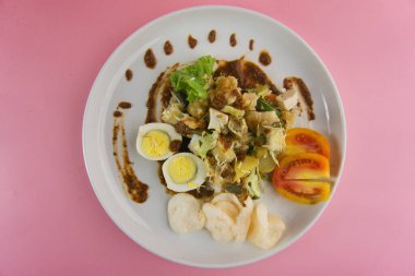 Canlı bir tabak gado-gado salatası. İçinde taze sebzeler, haşlanmış yumurtalar ve fıstık sosuyla servis edilen garnitür var.