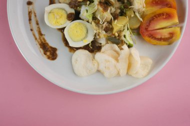 Canlı bir tabak gado-gado salatası. İçinde taze sebzeler, haşlanmış yumurtalar ve fıstık sosuyla servis edilen garnitür var.