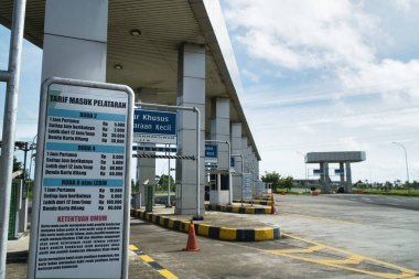 Araç park ücretleri için net fiyatlandırma bilgilerini gösteren modern bir gişe. Konum, parlak mavi gökyüzü altında organizasyon ve müşteri kolaylığı için geliştirmeler içerir