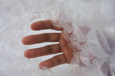 İnsan eli, narin şeffaf baloncuk ambalajından geçer, keşif, izolasyon ve insan etkileşimi kavramlarını anımsatır. Dokuya, şeffaflığa ve ışık ile maddenin etkileşimine vurgu yapar