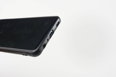 Close-up view of a black smartphone on a white background focusing on its lower edge featuring charging and headphone ports clipart