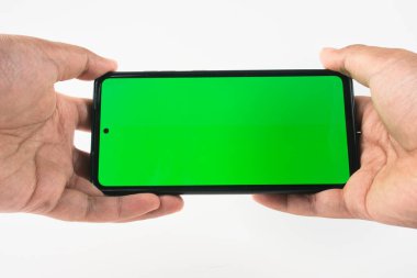 Canlı yeşil ekran içeren akıllı telefonu tutan ellerin yakın çekimi, modelleme veya dijital içerik görüntüleme amaçları için kullanışlı. Uygulama kavramlarını, reklamları veya teknoloji tasarımlarını sergilemek için mükemmel.