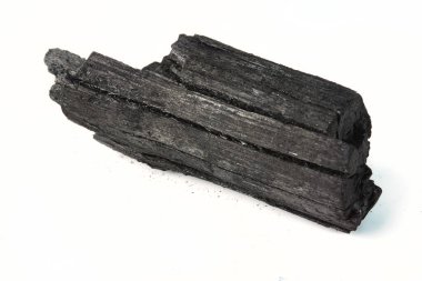 Beyaz bir yüzeye izole edilmiş doğal kömür parçasının detaylı görüntüsü.