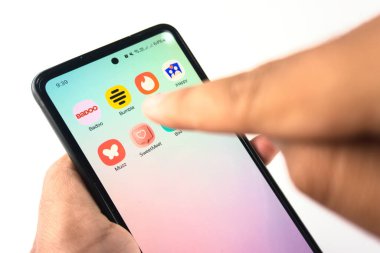 Jakarta, Endonezya - Şubat 2025, 27: Çeşitli popüler tarih uygulamaları simgelerini gösteren, modern online çöpçatanlık ve bağlanabilirliği sembolize eden akıllı telefon ekranı ile etkileşime giren bir elin yakın görüntüsü